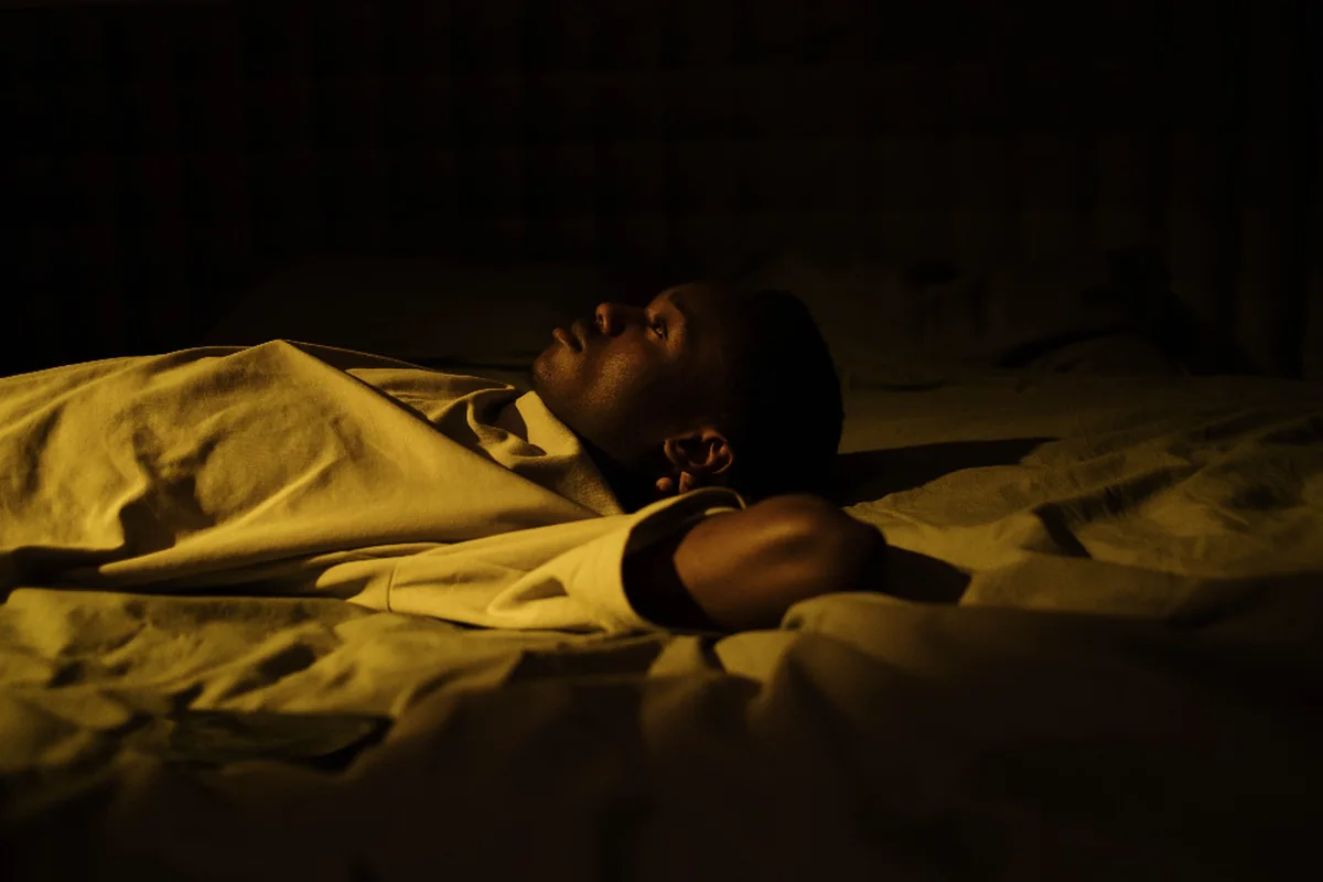 A person lying awake in bed at night, lost in thought.