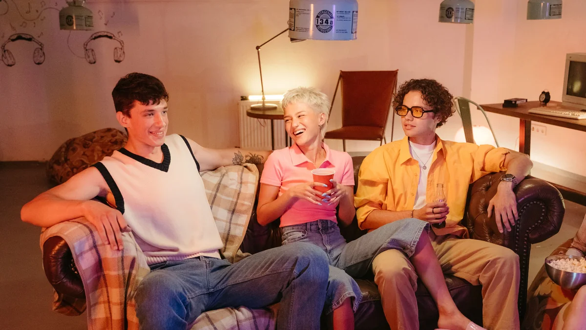 Young friends chatting and laughing together at a casual house party.