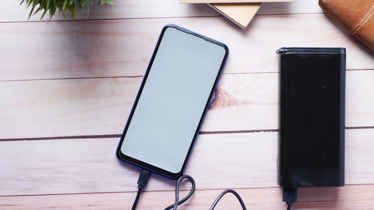 Smartphone showing very low battery beside a portable charger
