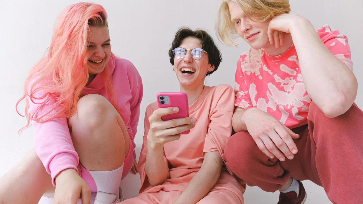 Friends laughing together while looking at a funny photo on a smartphone