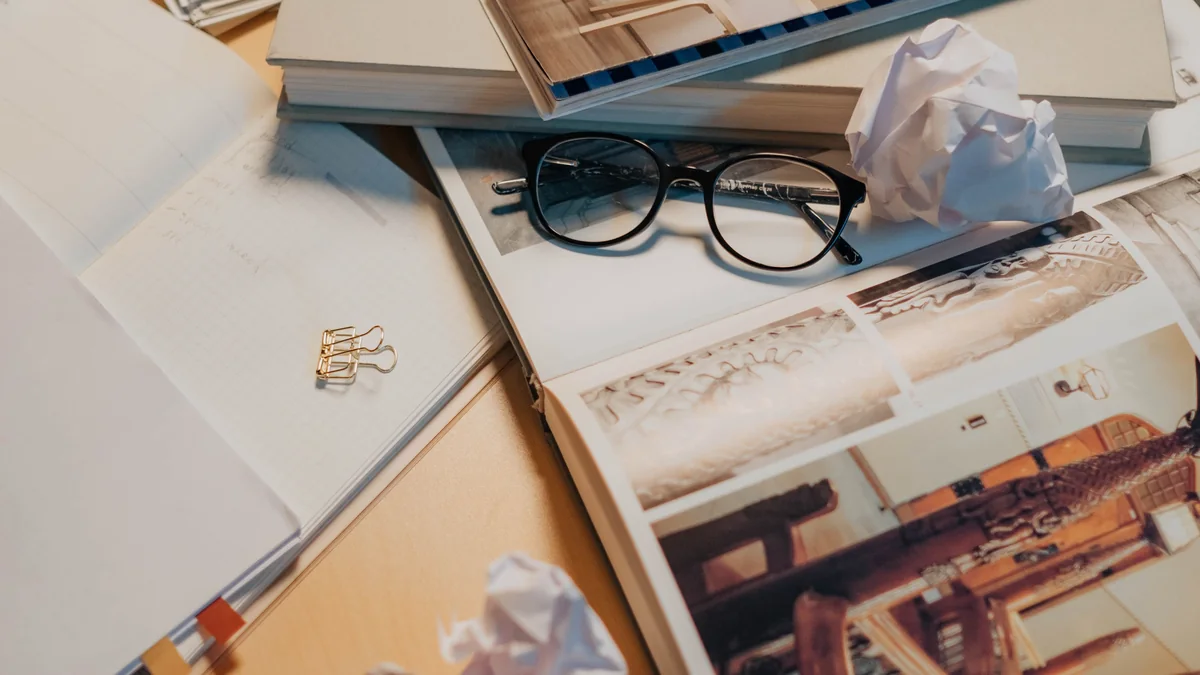 Cluttered work desk covered with everyday items and papers