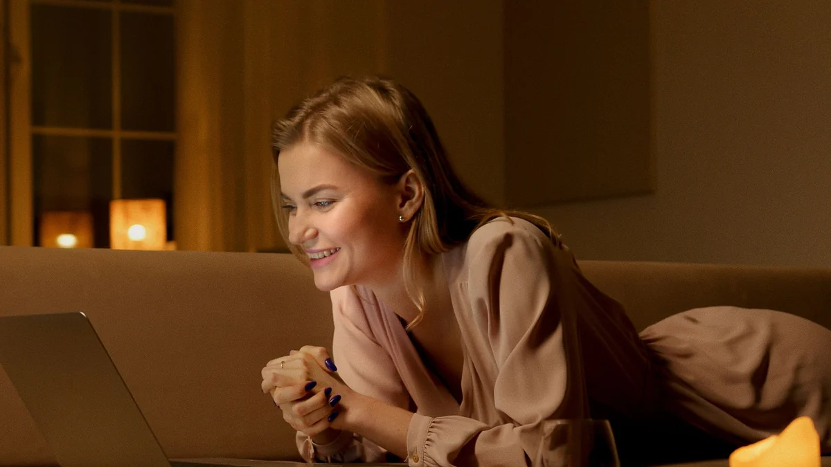 Woman relaxing on a sofa with a laptop during a cozy night at home