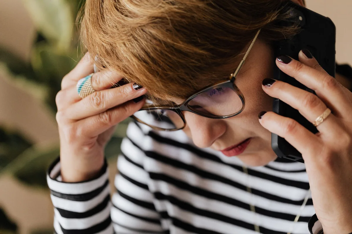 A worried woman taking a stressful phone call in an office.