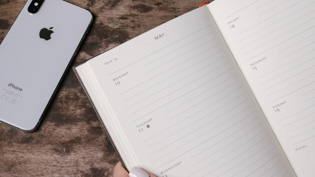 A weekly planner, smartphone and coffee arranged for weekend planning.