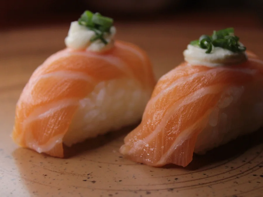 Salmon nigiri sushi pieces on a plate.