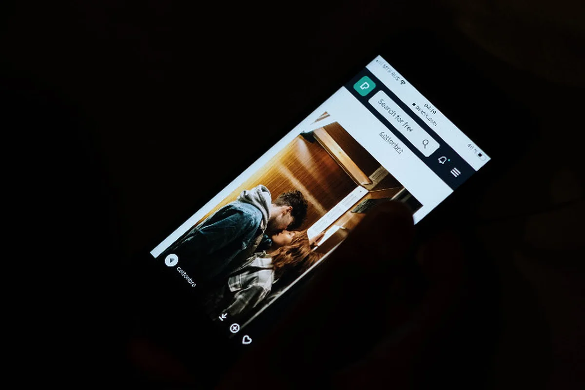 A smartphone glowing in a dark room during a late-night scroll.