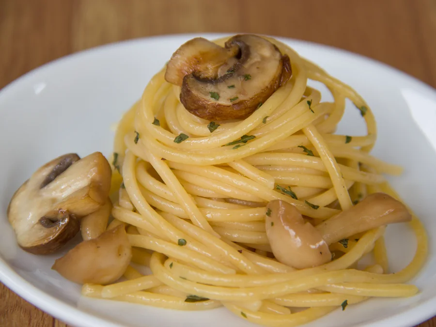 Mushroom pasta topped with cooked mushrooms.