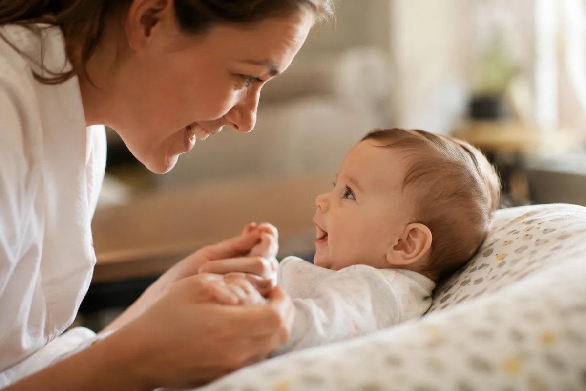 Baby looking closely at a familiar caregiver while listening to her voice
