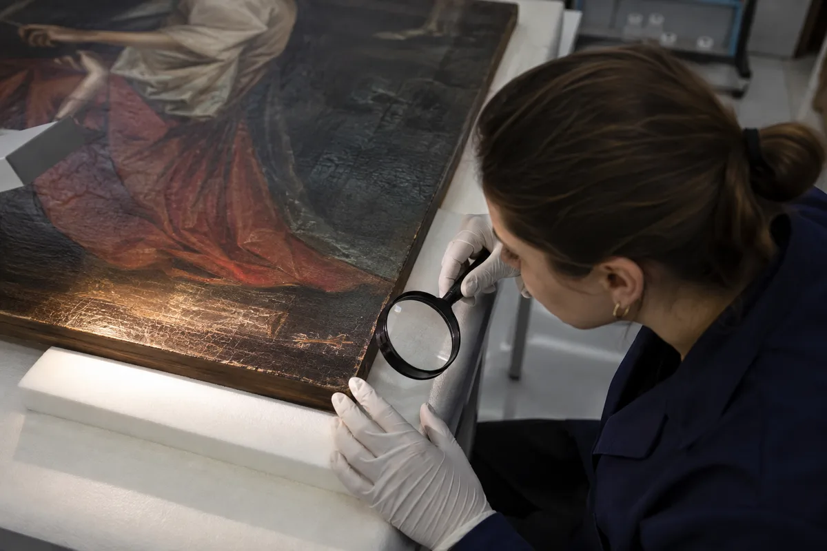 Conservator examining an artist’s signature on an old painting