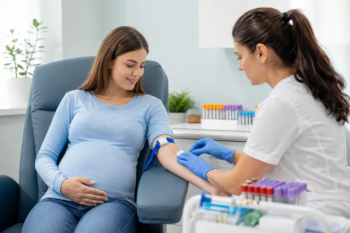 Healthcare professional preparing a blood sample from a pregnant woman for noninvasive prenatal testing.